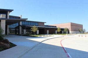 NWISD Lance Thompson ES Wide view of a modern school or institutional building with large glass windows, landscaped entryway, and a curved driveway.